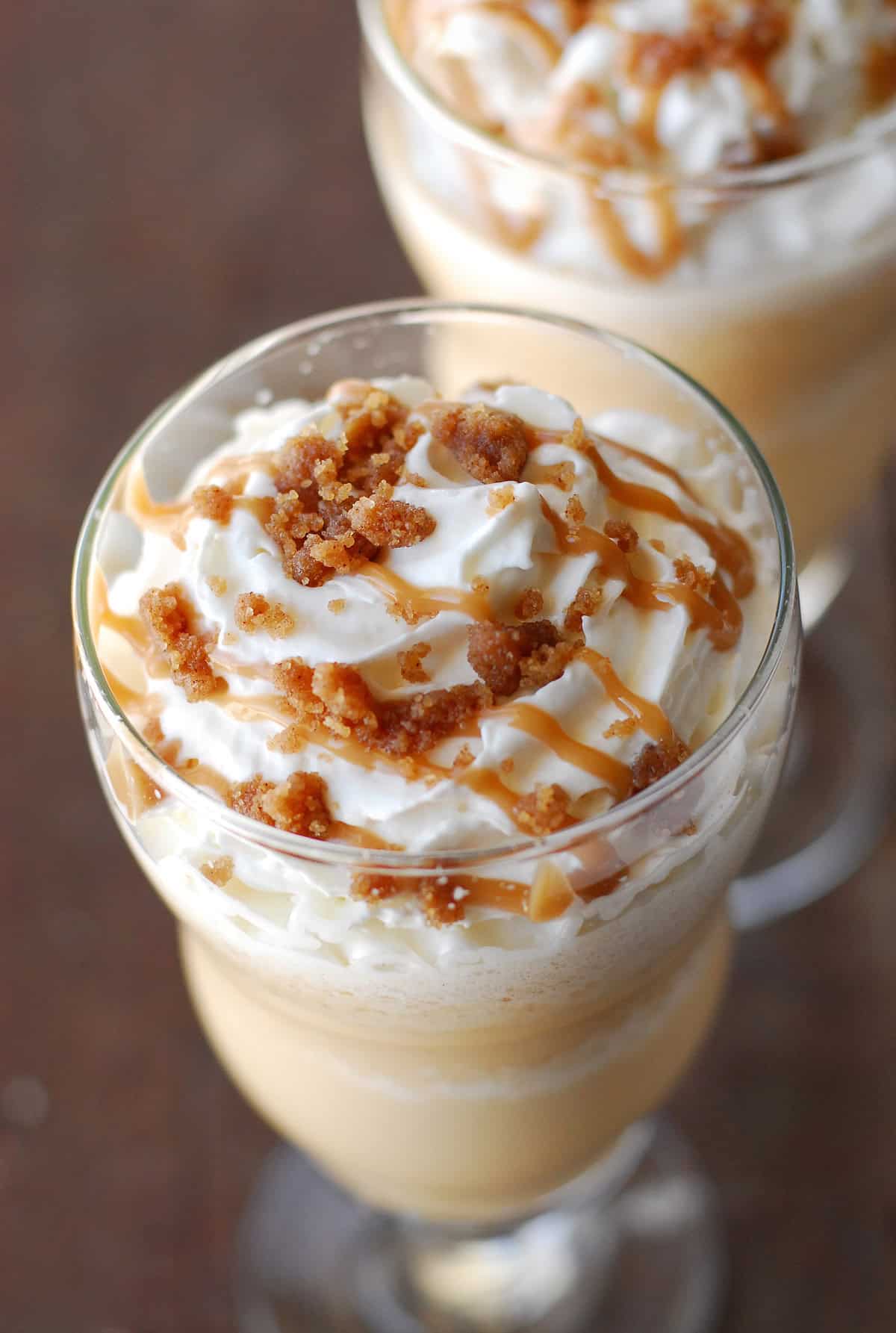 A glass holding cinnamon streusel coffee cake frappe topped with whipped cream and caramel.