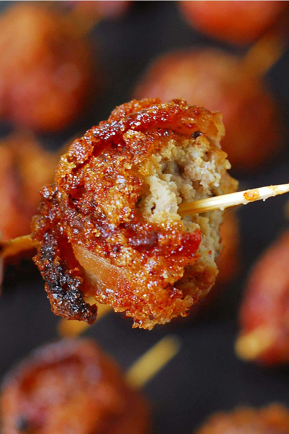 A meatball wrapped in bacon on a toothpick.