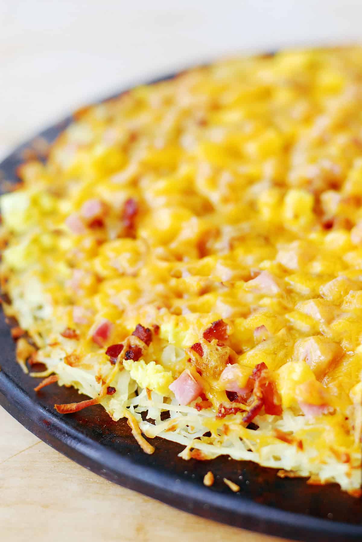 Breakfast pizza with a hashbrown crust and toppings.