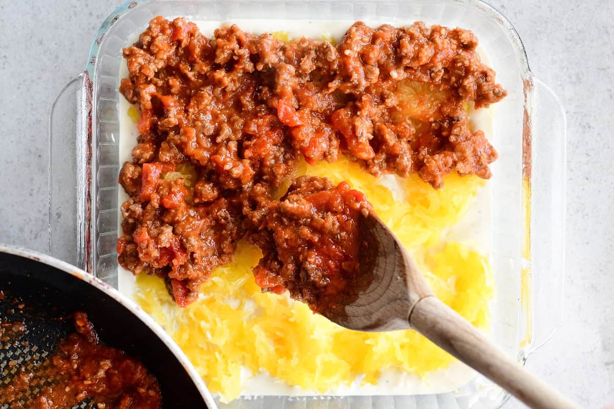 Adding meat sauce to million dollar spaghetti squash casserole.