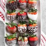 decorated chocolate covered strawberries on a white speckled platter