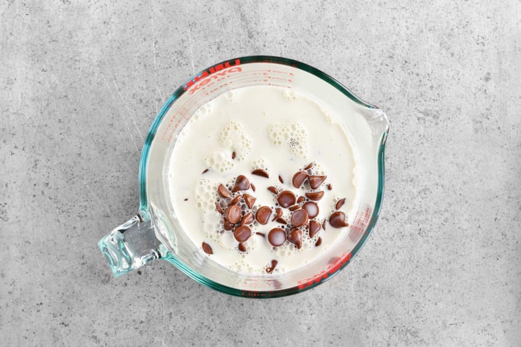 A mixing bowl with cream and chocolate chips inside.