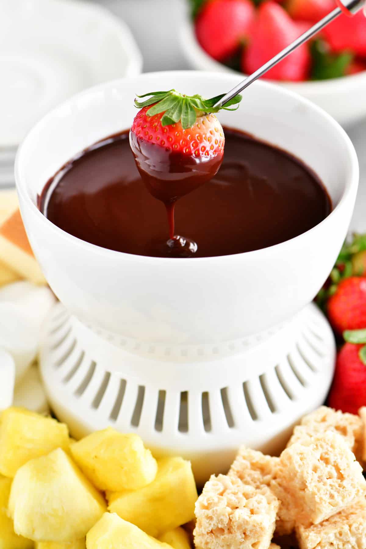 A strawberry being dipped into the chocolate fondue.