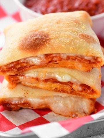 sliced pizza pockets on red and white parchment.