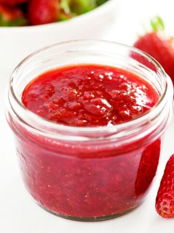 A jar holding strawberry sauce.