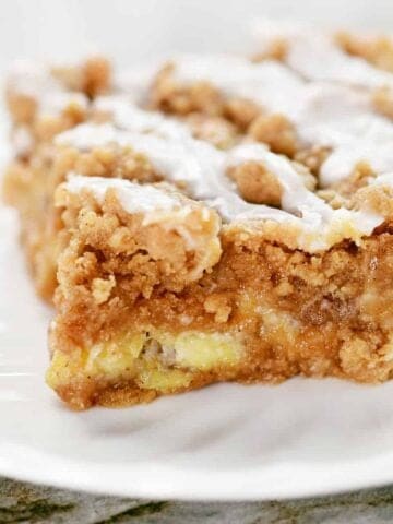 A slice of an apple bar with icing on top.