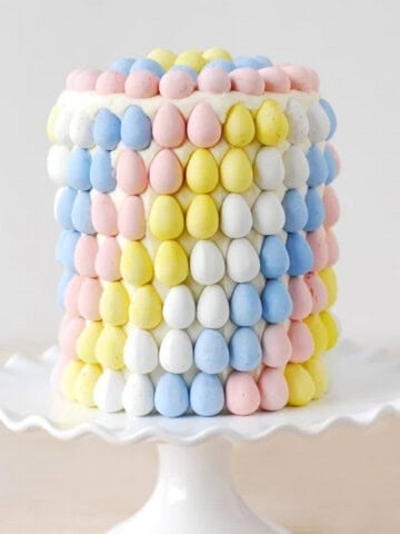 Cadbury mini eggs layer cake on a white cake stand.