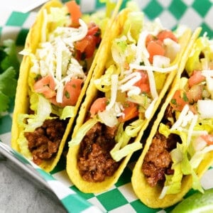 Three slow cooker tacos in a hard shell with toppings.