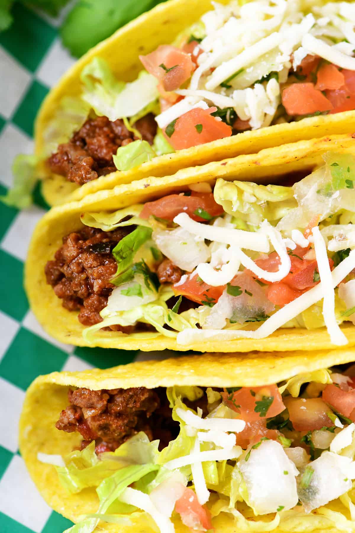 Three tacos with ground beef and toppings.