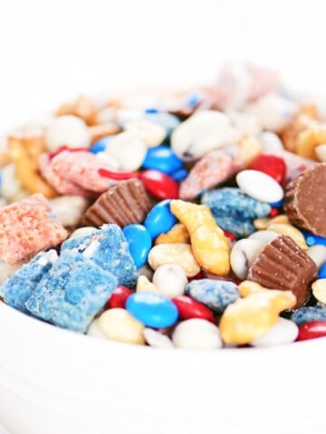 Red white and blue trail mix in a white bowl.