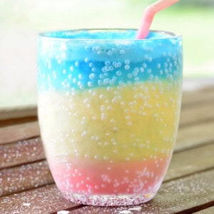 Layered sunset slushie in a clear cup with a pink straw.