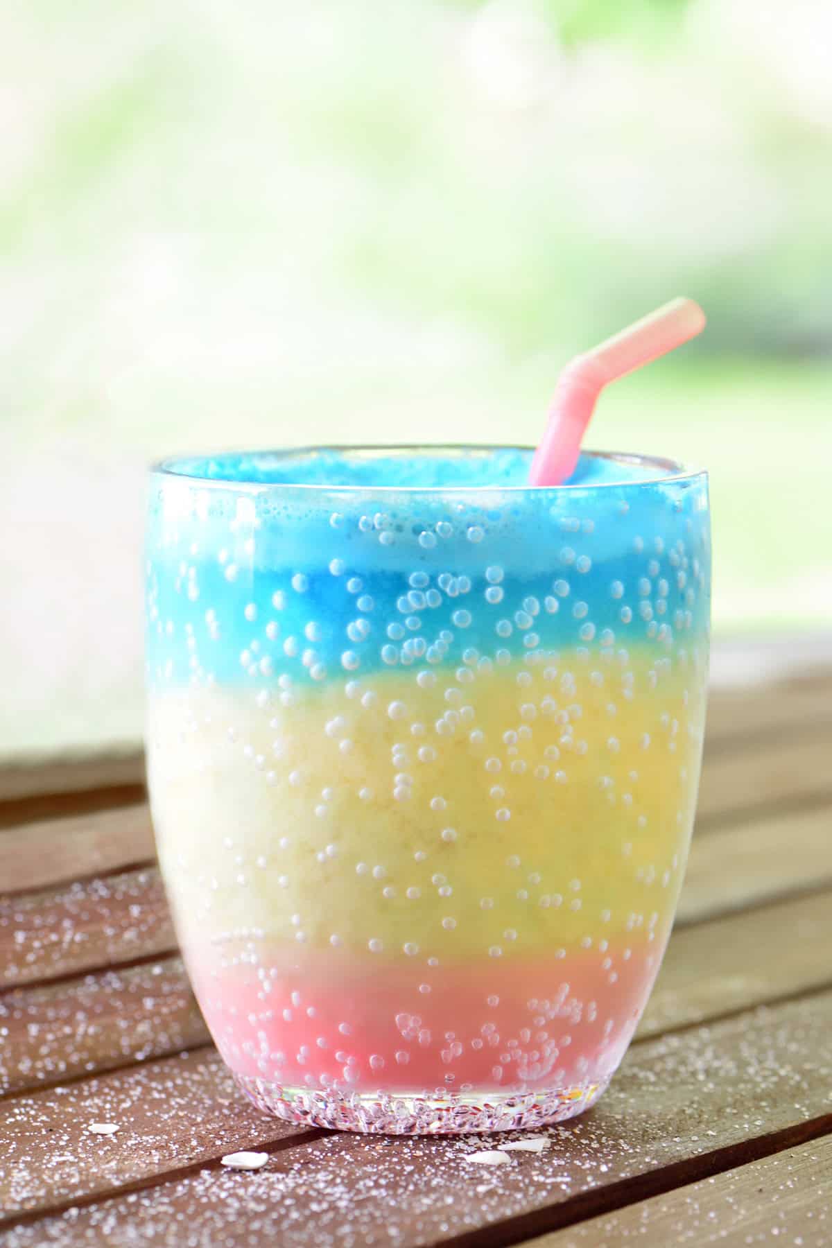 Layered sunset slushie in a clear cup with a pink straw.