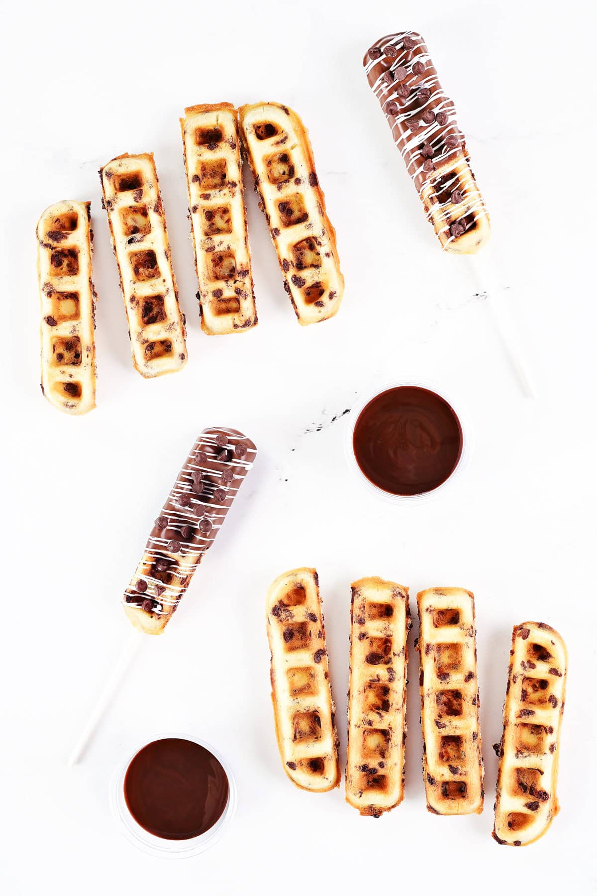 Chocolate chip waffle sticks, chocolate dipped waffle pops, and chocolate syrup in cups.