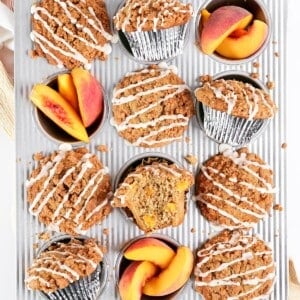 Peach muffins and sliced peaches in a muffin pan.