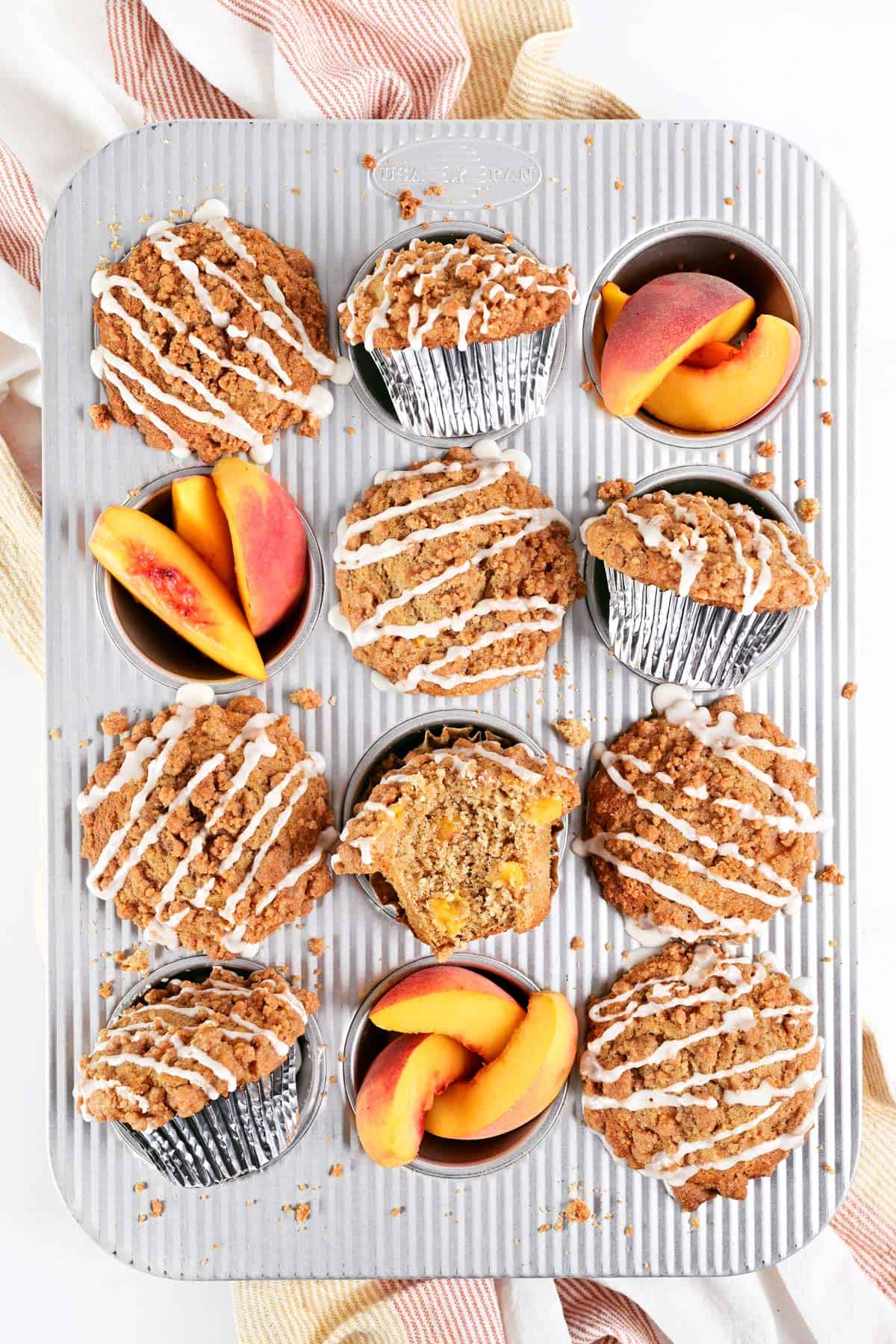 Peach muffins and sliced peaches in a muffin pan.