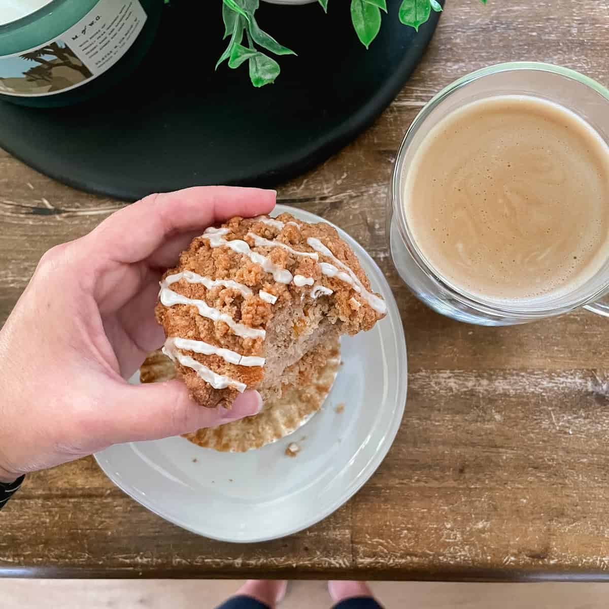 A hand holding a peach muffin.