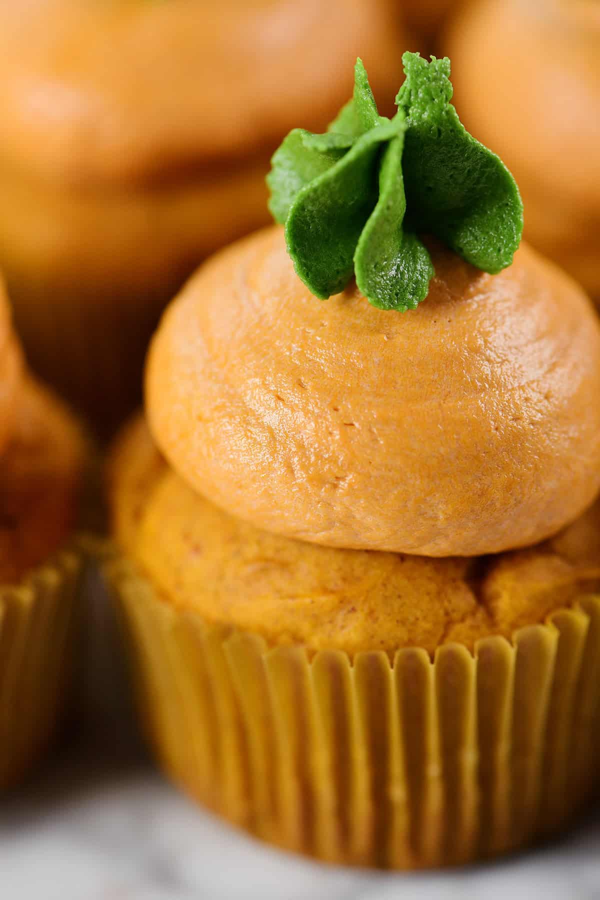 Orange and green buttercream frosting on a pumpkin cupcake.