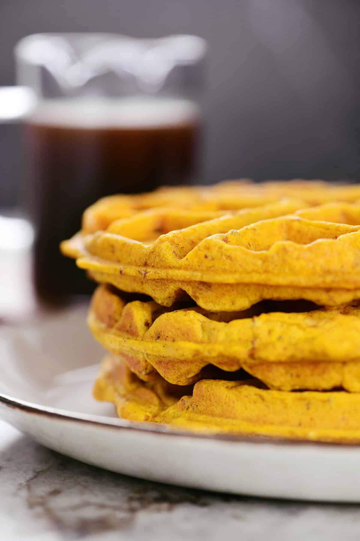 Three pumpkin waffles on a plate.