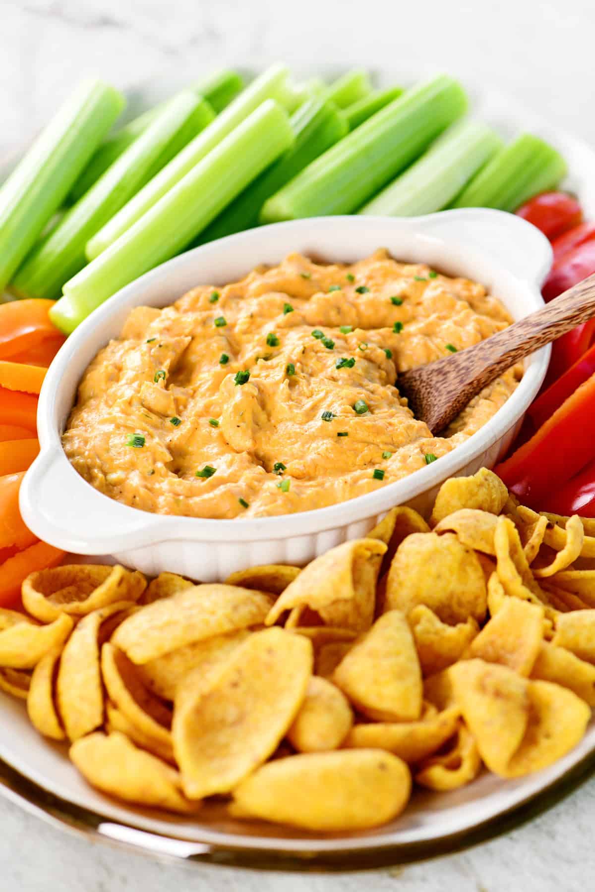 Slow cooker buffalo chicken dip on a platter with veggies and chips.