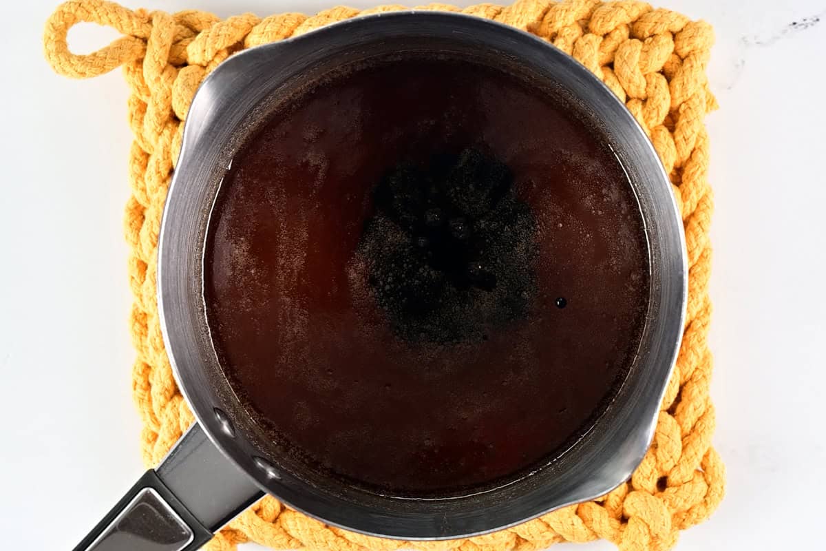 A saucepan on a yellow pot holder.