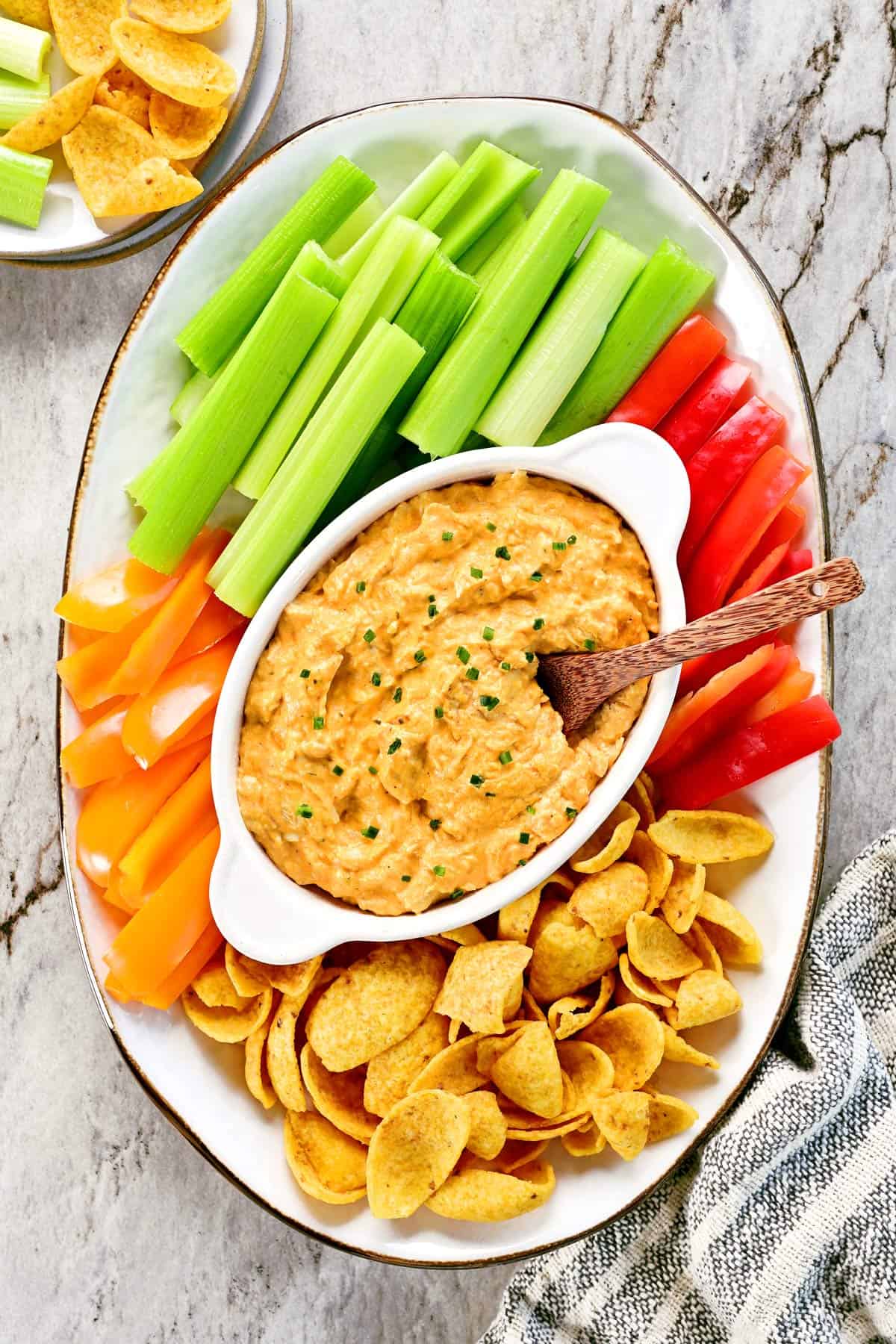 Slow cooker buffalo chicken dip on a platter with veggies and chips.