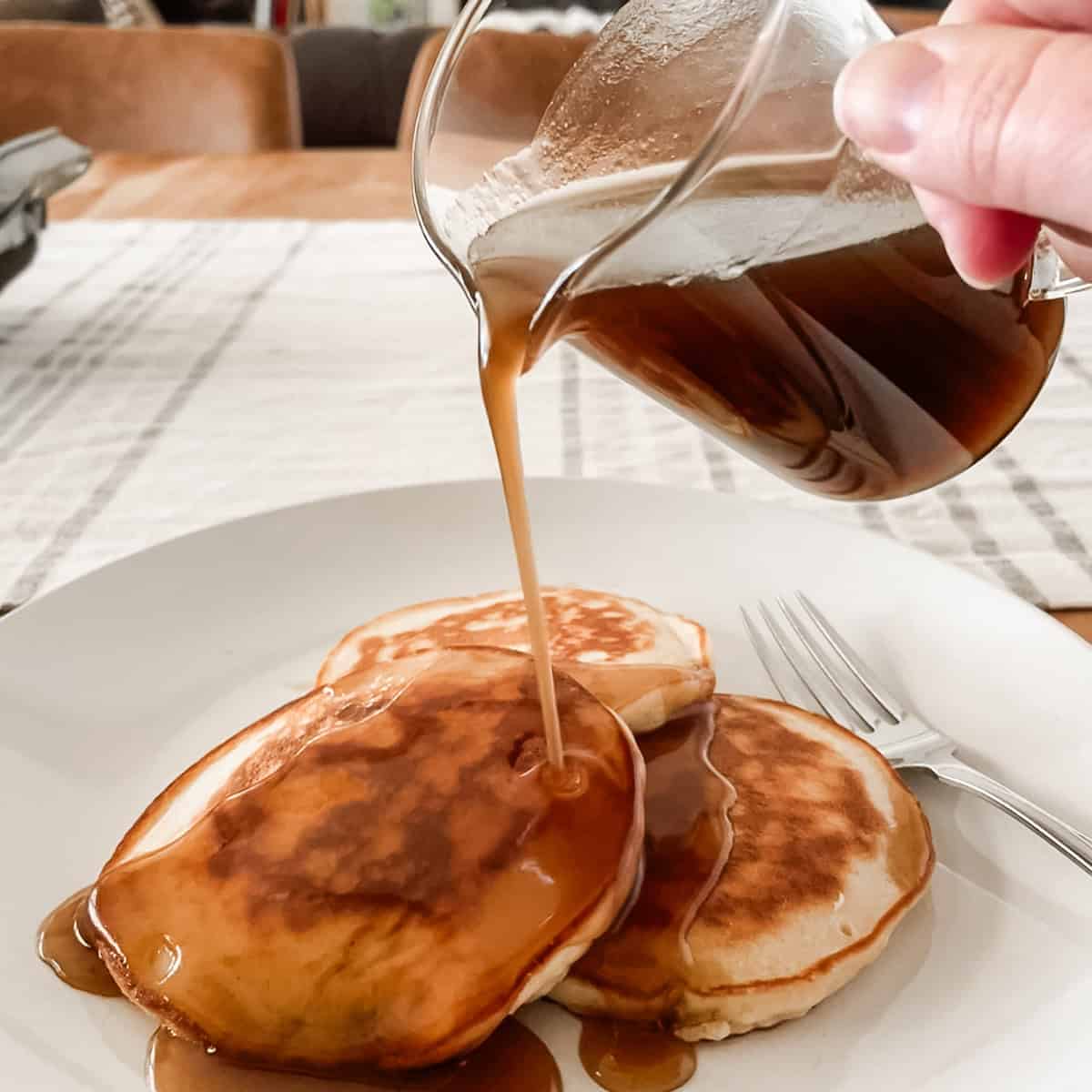 Tonia Larson pouring homemade maple syrup on pancakes.