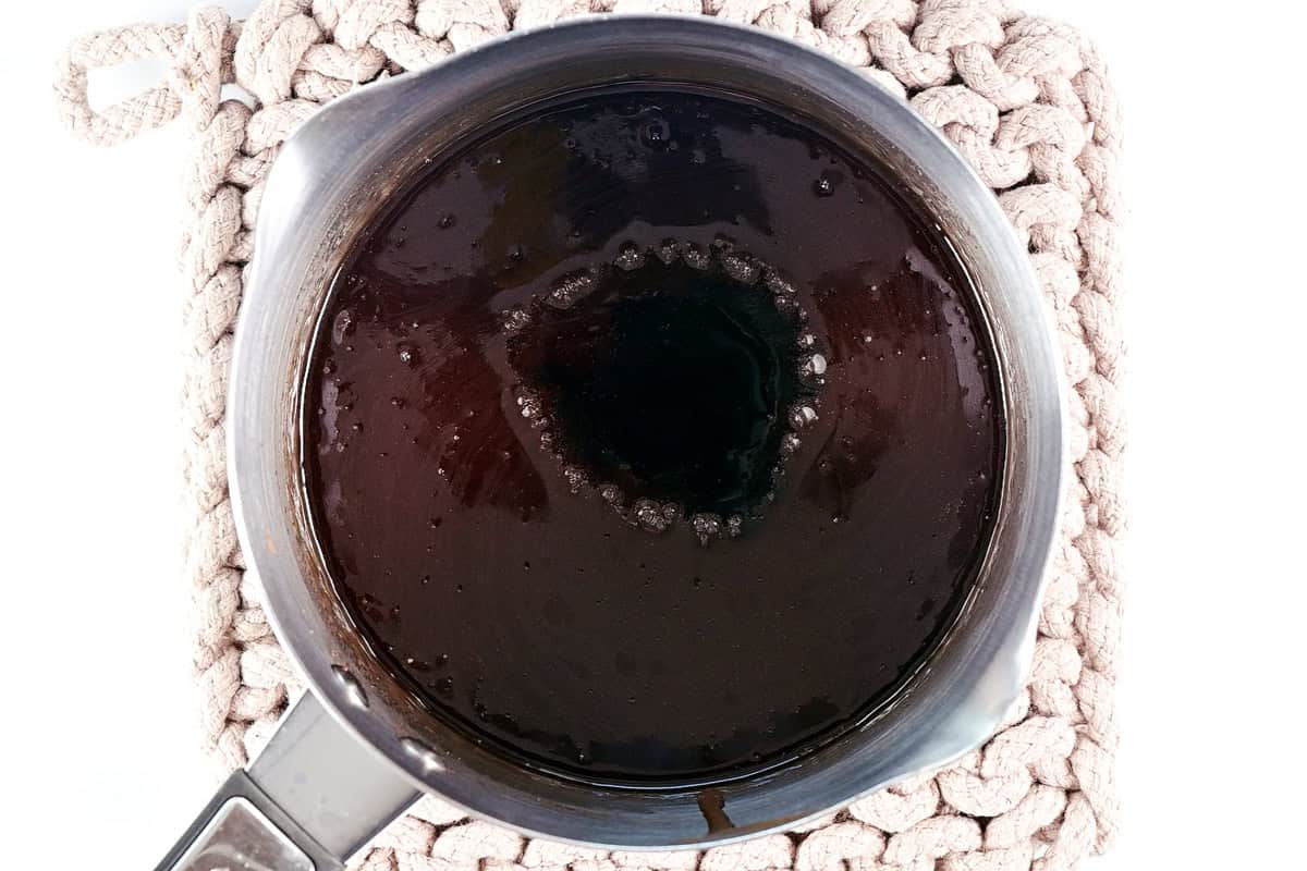 A saucepan with dark liquid on a trivet.