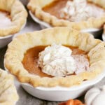 Individual mini pumpkin pies with whipped cream on top.