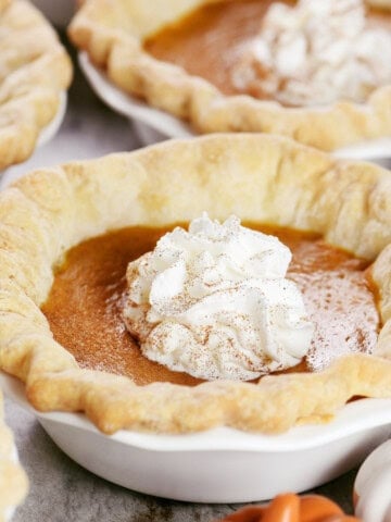 Individual mini pumpkin pies with whipped cream on top.