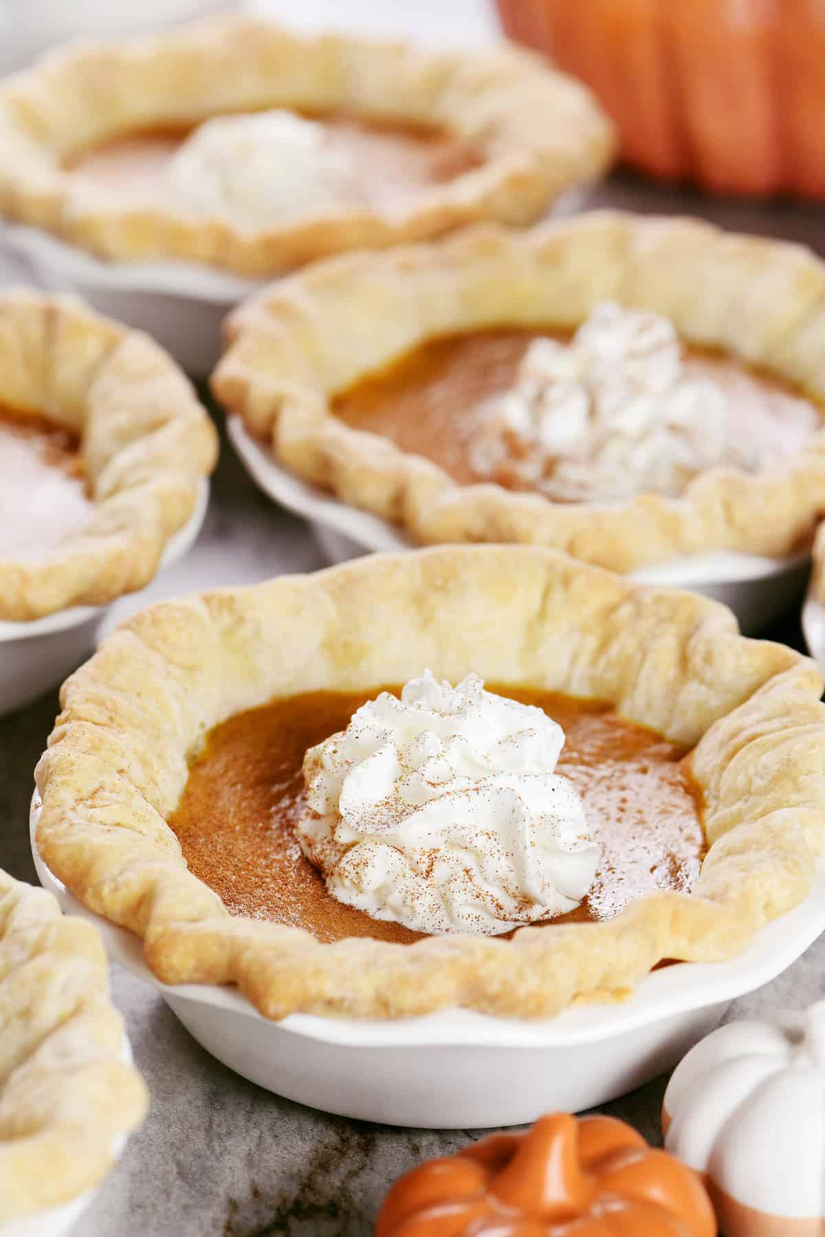 Individual mini pumpkin pies with whipped cream on top.