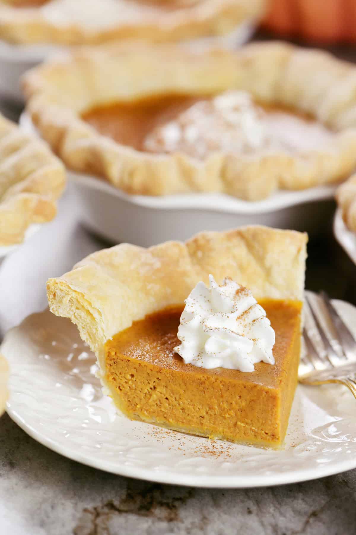 Slice of an individual pumpkin pie with whipped cream on top.