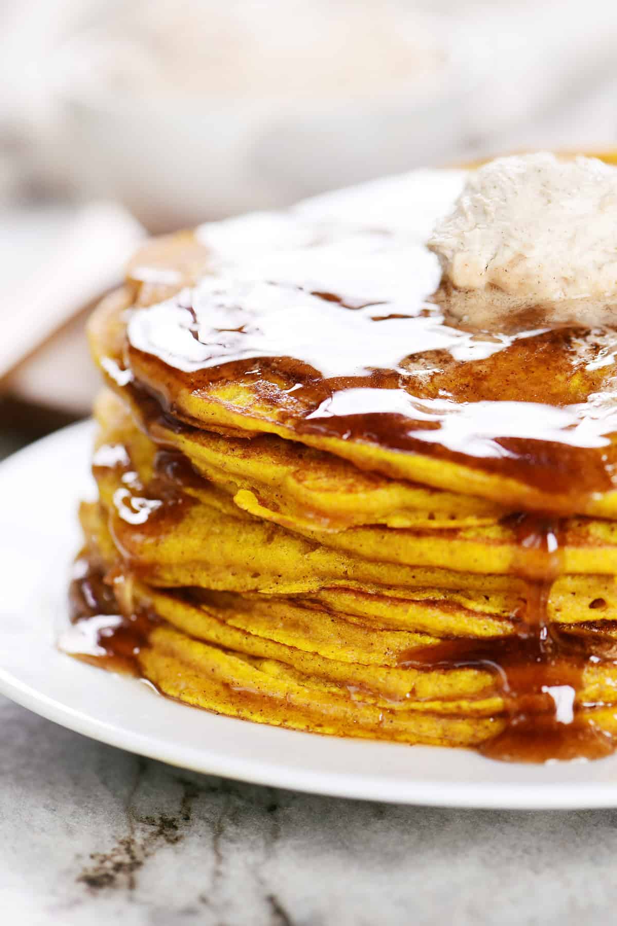 Side view of a stack of pumpkin pancakes with syrup.