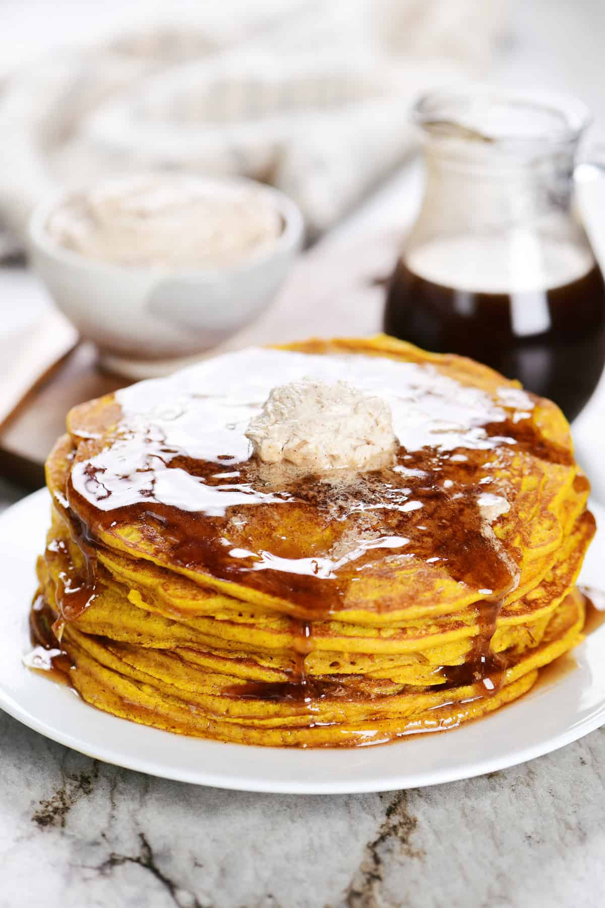 Stack of pumpkin pancakes on a plate with syrup.