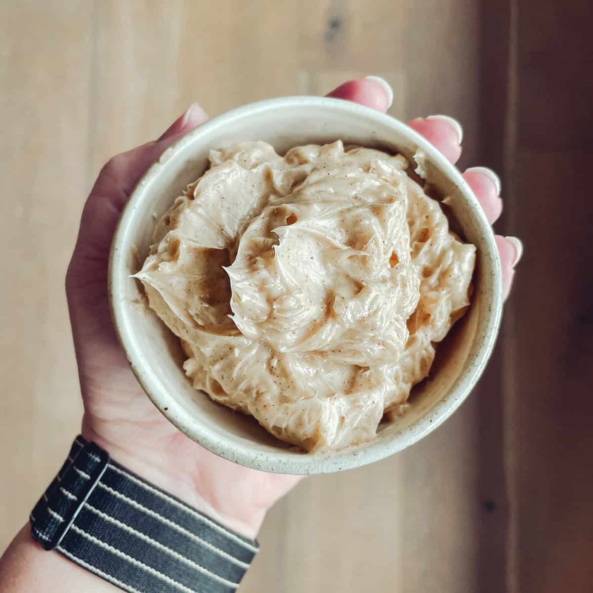 A hand holding honey cinnamon butter.