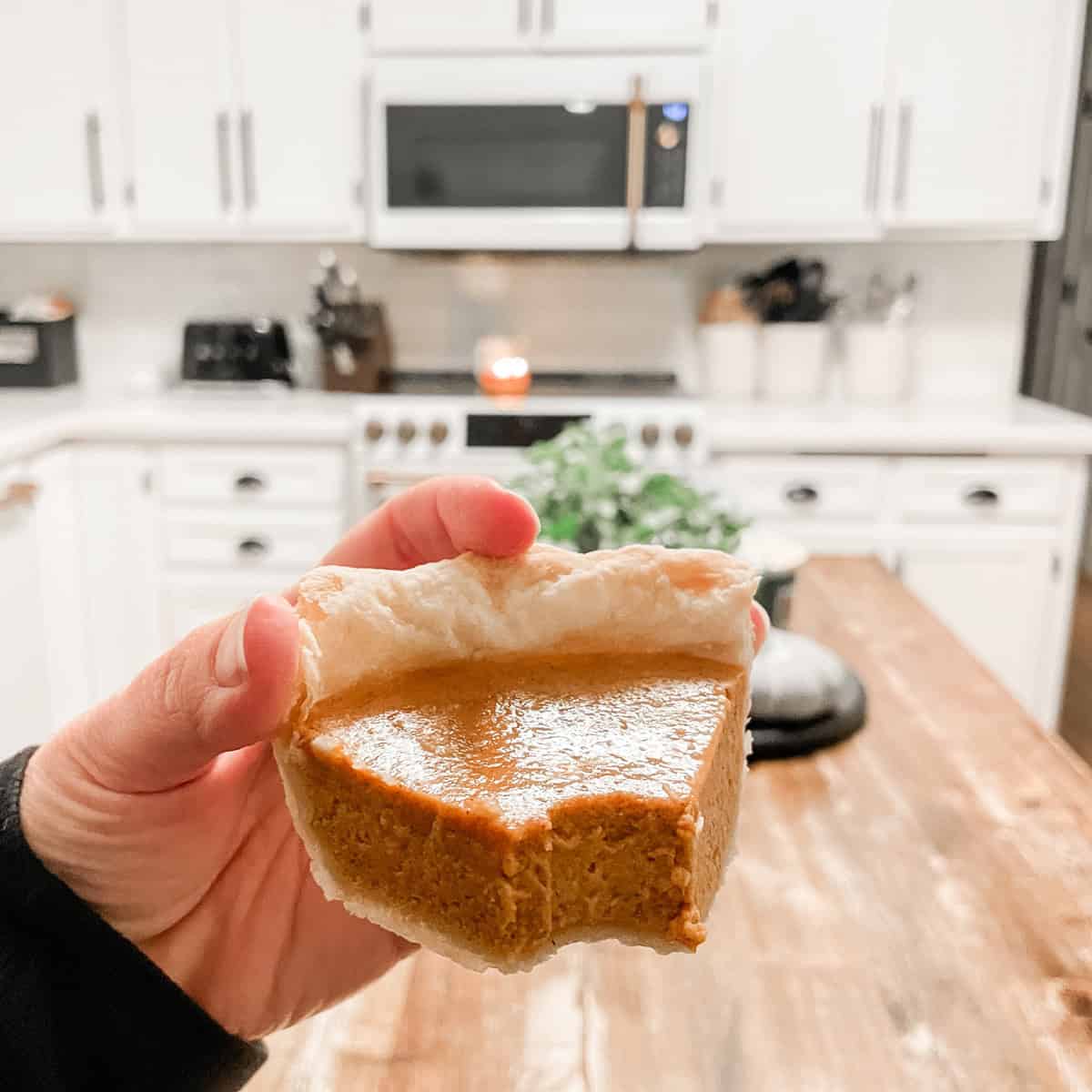 Tonia Larson holding a slice of pumpkin pie in the kitchen.