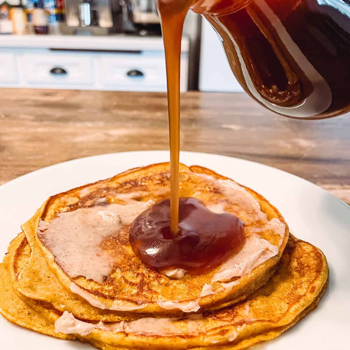 Pouring cinnamon syrup on pancakes.