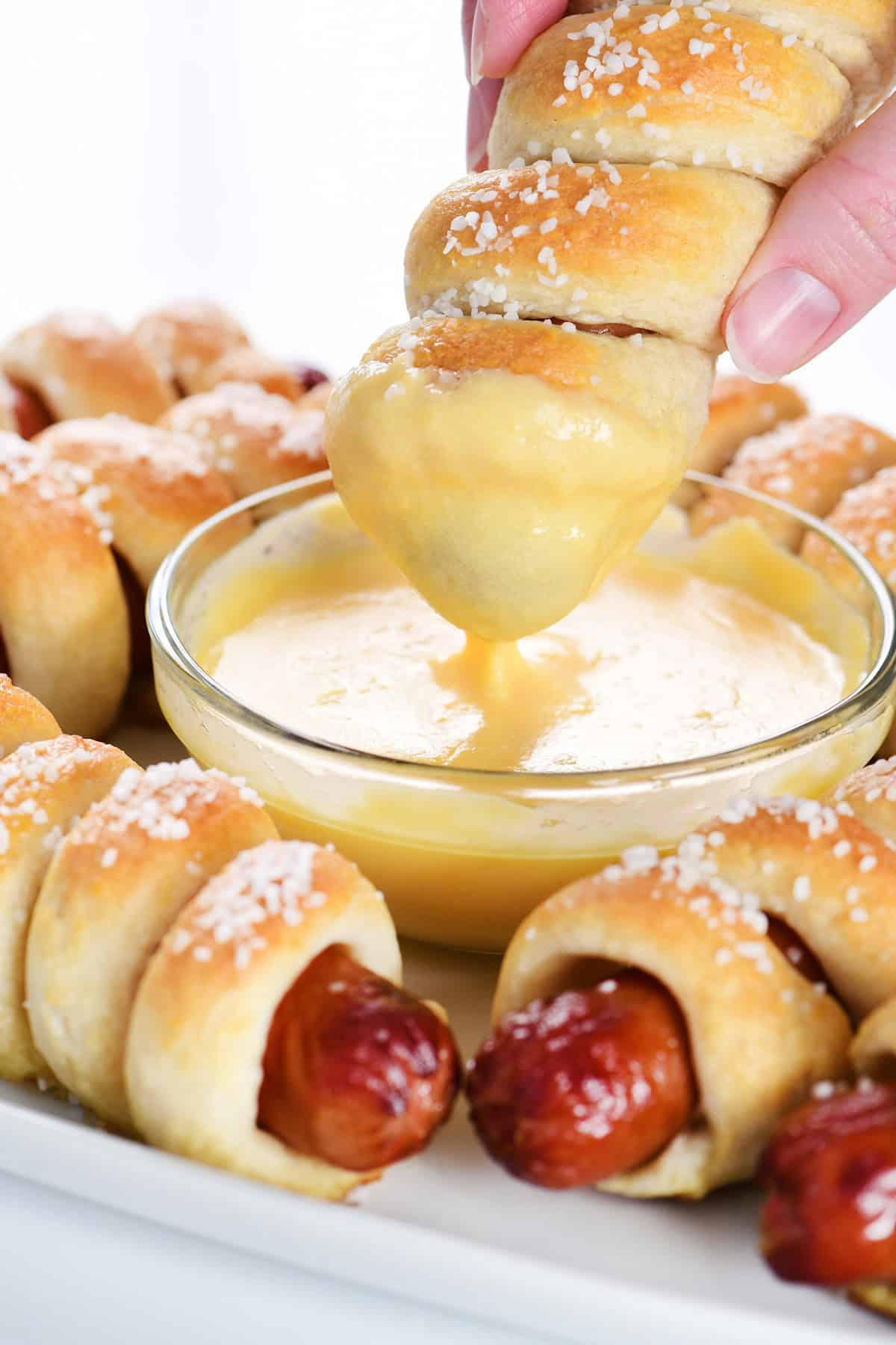 Dipping a pretzel dog in cheese sauce.