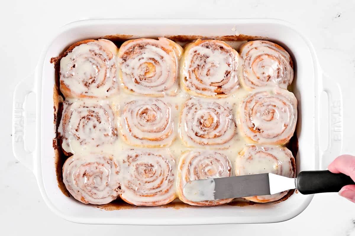 Spreading frosting on no yeast cinnamon rolls.