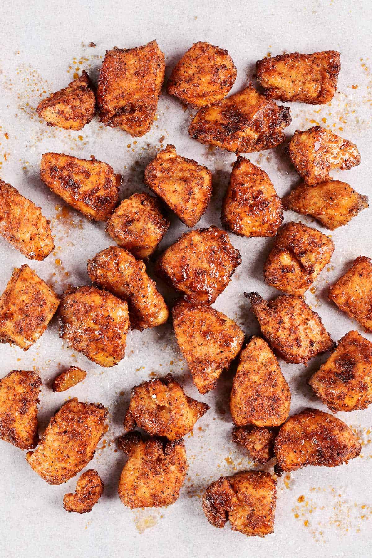 Spicy air fryer chicken bites on parchment paper.