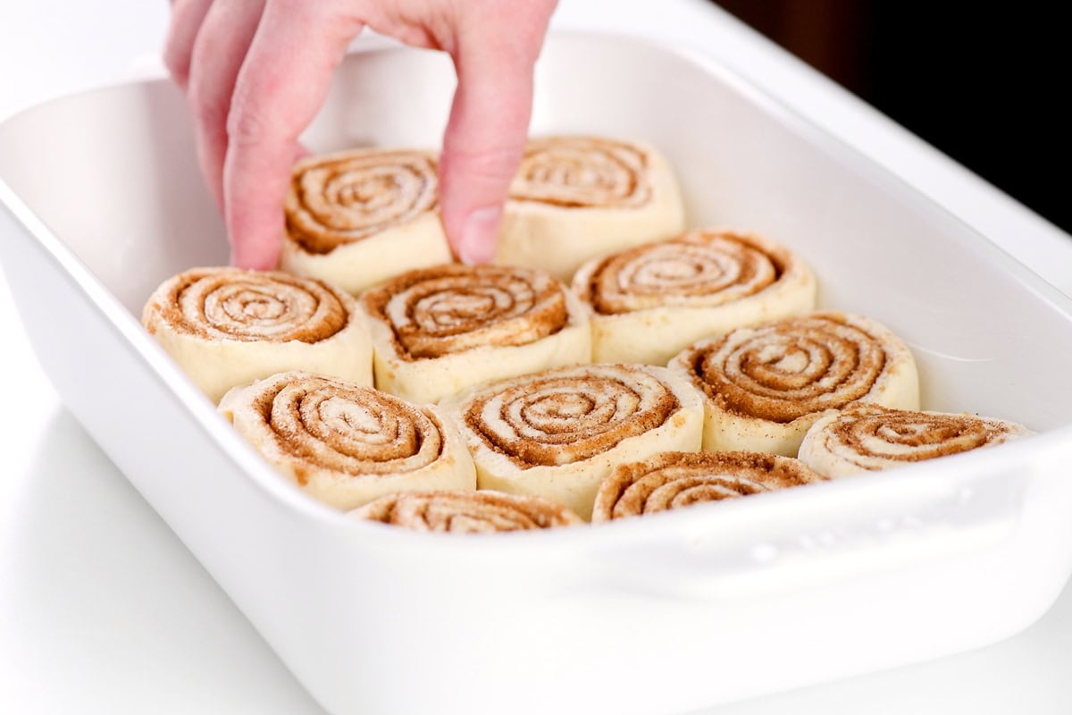 Adding cinnamon rolls to the pan.