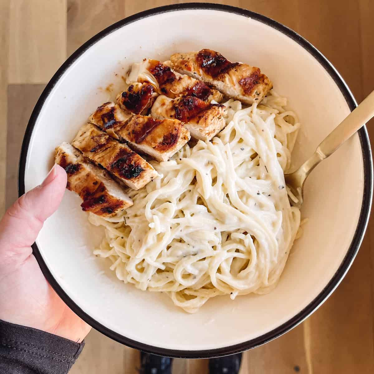 Tonia Larson holding a bowl of creamy angel hair pasta and chicken.