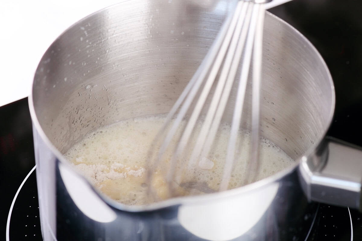 Whisking flour and butter in a saucepan.