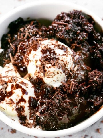 Slow cooker chocolate pudding cake in a bowl with vanilla ice cream.